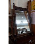 An antique oak framed swing dressing table mirror with carved stylised bird's-head decoration to