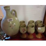 A Northcott studio pottery wine flagon with six goblets decorated with hand painted flowers on an