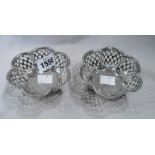 A pair of silver hexafoil lobed bon bon dishes with pierced decoration, set on triple scroll