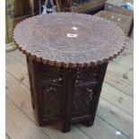 An Indian carved hardwood circular tea table with floral decoration, set on a carved and pierced