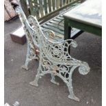 A pair of cast iron bench ends of Rococo scroll form with later painted finish