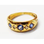 An 18ct. gold gypsy set three stone cornflower blue sapphire and tiny diamond ring - size K