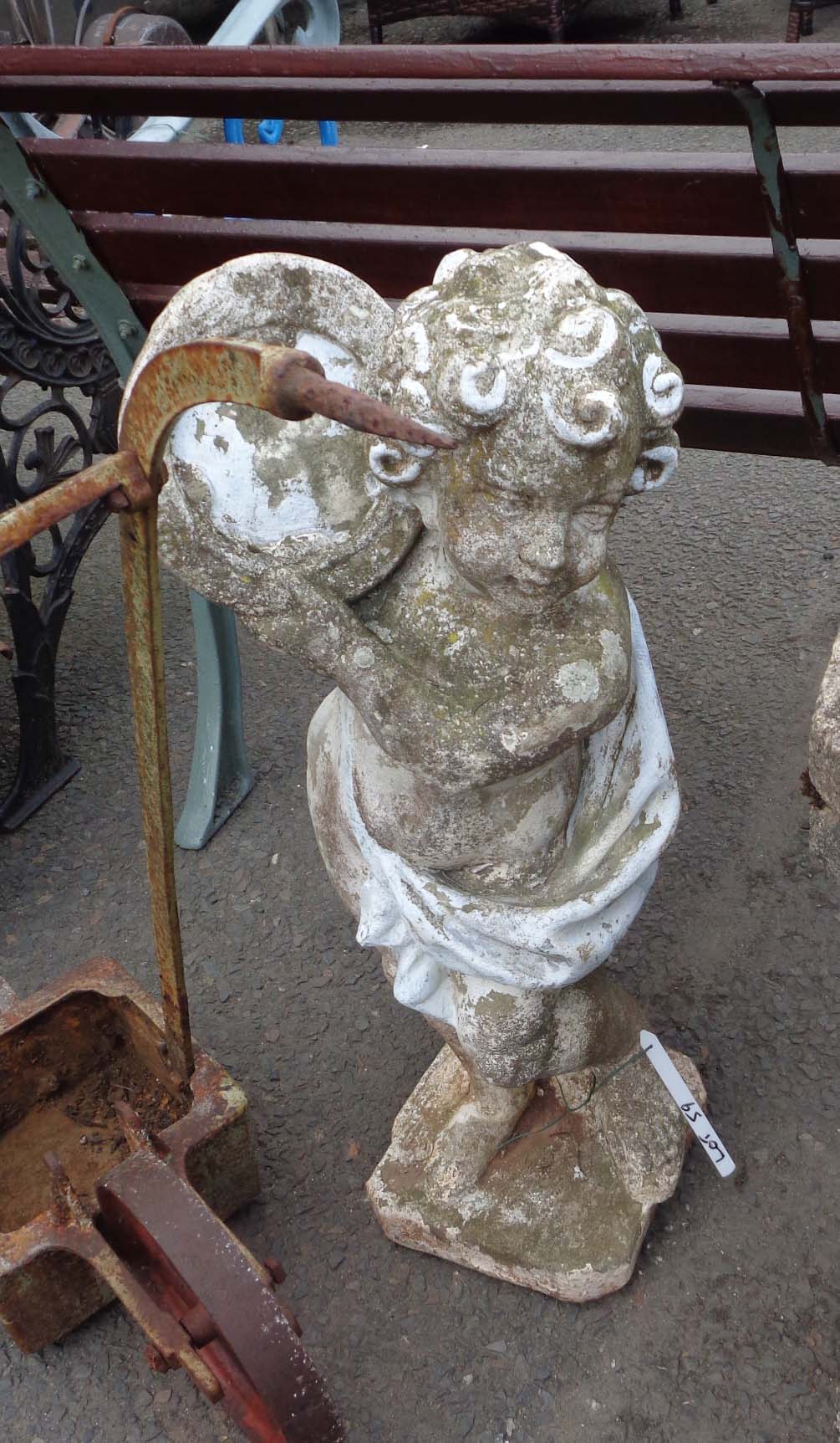 An old concrete garden statue depicting a cherub playing a tamborine