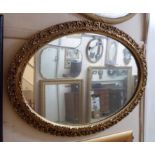 A modern ornate gilt framed oval wall mirror with pierced scroll border