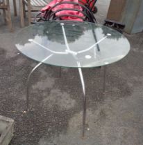 A modern glass topped table with chrome plated legs