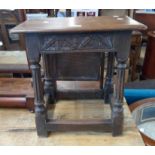 An old oak joint style stool with carved decoration, set on turned and fluted supports with an