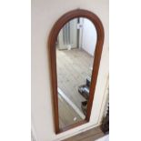 A modern stained wood framed arched wall mirror