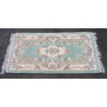 A Chinese washed wool rug with floral scroll decoration on pale green ground - 1.53m X 79cm