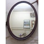 A 1920's wood grained framed bevelled oval wall mirror - minor damaged to beading