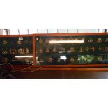 Two wooden display cases containing a quantity of military cap badges including The Royal Scots