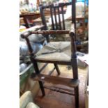 An old oak framed child's lathe back highchair with woven rush seat, set on turned supports