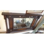 An early 20th Century stained oak framed overmantel mirror with flanking barley twist pillars and