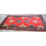 A Middle Eastern handmade wool rug with four central medallions and geometric design within a