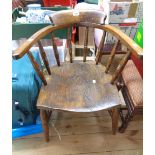 An antique smoker's bow elbow chair with spindle back and moulded solid elm seat, set on turned