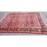 A hand made wool Persian pattern carpet with profuse floral scroll decoration within a decorative