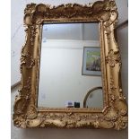 An ornate gilt gesso framed oblong wall mirror in the antique style with wide border - some loss