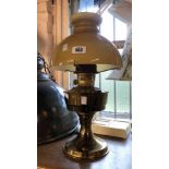 A vintage Aladdin brass oil lamp with clear glass chimney and amber opaque glass shade