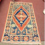 A vintage Afghan handmade wool rug with central diamond motif on a red and blue ground within a wide