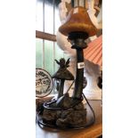 A modern cast resin table lamp depicting a fairy relaxing upon a toadstool with mottled amber