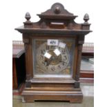 An early 20th Century German stained oak cased mantel clock with decorative dial and eight day