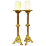 A pair of old gilt cast brass candlesticks of ecclesiastical form with decorative chased columns and