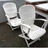 A pair of white plastic folding elbow chairs