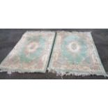 Two similar Chinese washed wool rugs with floral scroll decoration on pale green ground - staining -