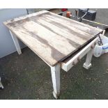 An old pine farmhouse kitchen table with plank top and single frieze drawer, set on a white
