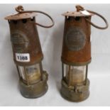 A pair of old brass and steel miner's safety lamps with plaques for The Protector Lamp and