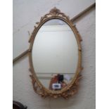 A small modern oval wall mirror with decorative cast Rococo style gilt metal border