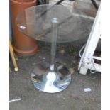 A retro glass topped circular table, set on chrome pillar and tapered base