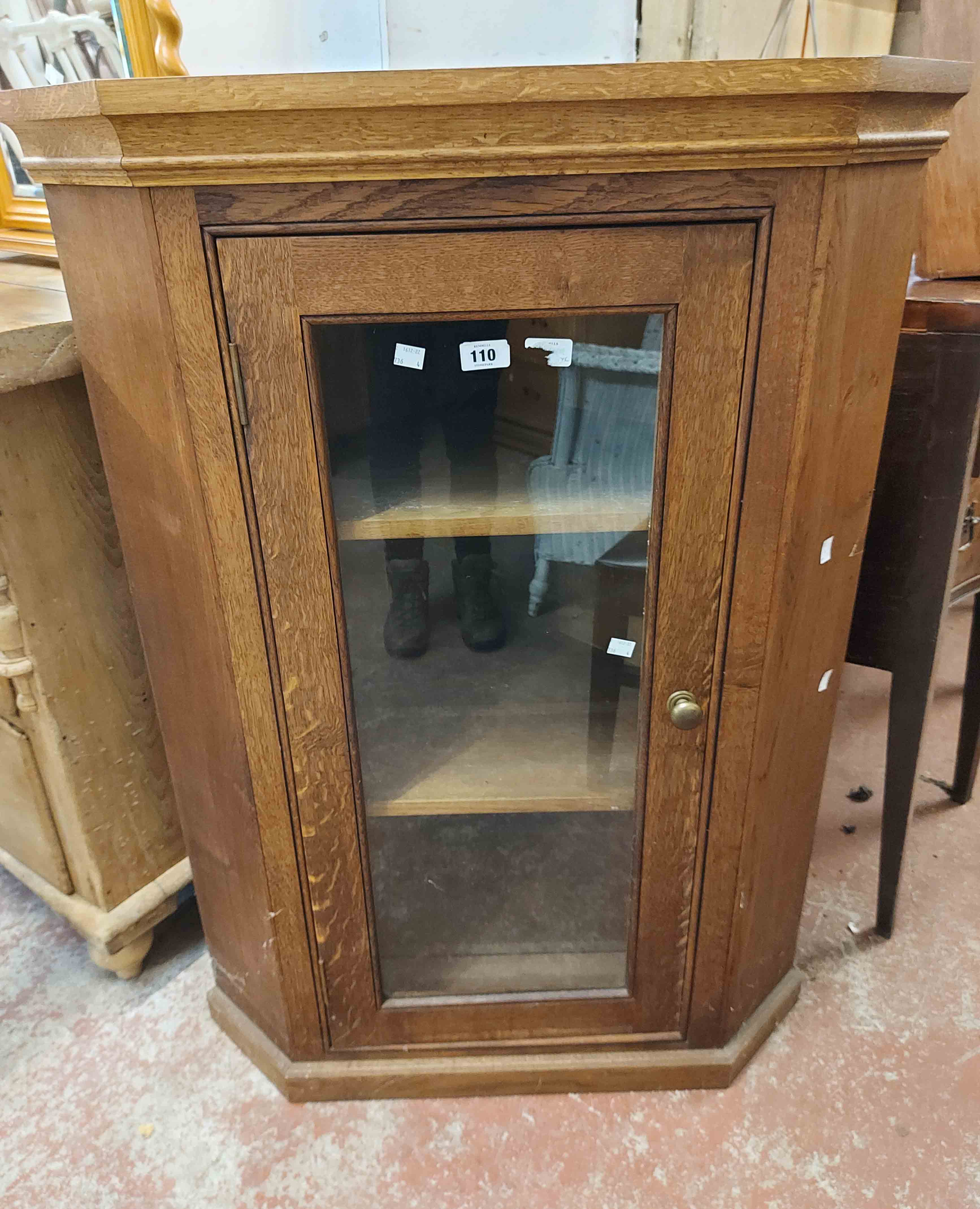A 78cm oak corner cabinet with canted sides enclosed by a glazed panel door