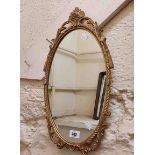 A small modern oval wall mirror with decorative cast Rococo style gilt metal border