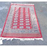 A modern handmade wool rug with triple repeat gul motifs to centre, within a wide decorative