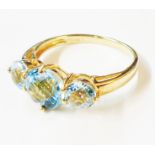 A 375 (9ct.) gold ring, set with three round cut pale blue topaz stones - size O - boxed