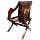 A late Victorian carved oak Glastonbury elbow chair with decorative back rail, shaped armrests and