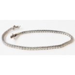 A marked 18k white metal tennis/inline bracelet, each of the links set with an individual