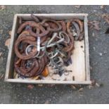 A wooden drawer containing a collection of horseshoes