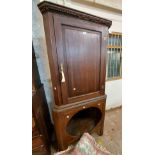 A 90cm antique stained oak freestanding corner cabinet with remains of dentil cornice and