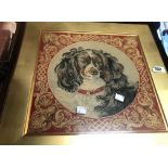 A Victorian needlework panel depicting a spaniel dog, set in decorative carved rosewood frame