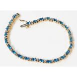 A 375 (9ct.) gold bracelet, set with oval blue topaz stones interspersed with pairs of tiny diamonds