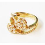 A marked 14K yellow metal split double band ring, with diamond encrusted twin flowerheads and