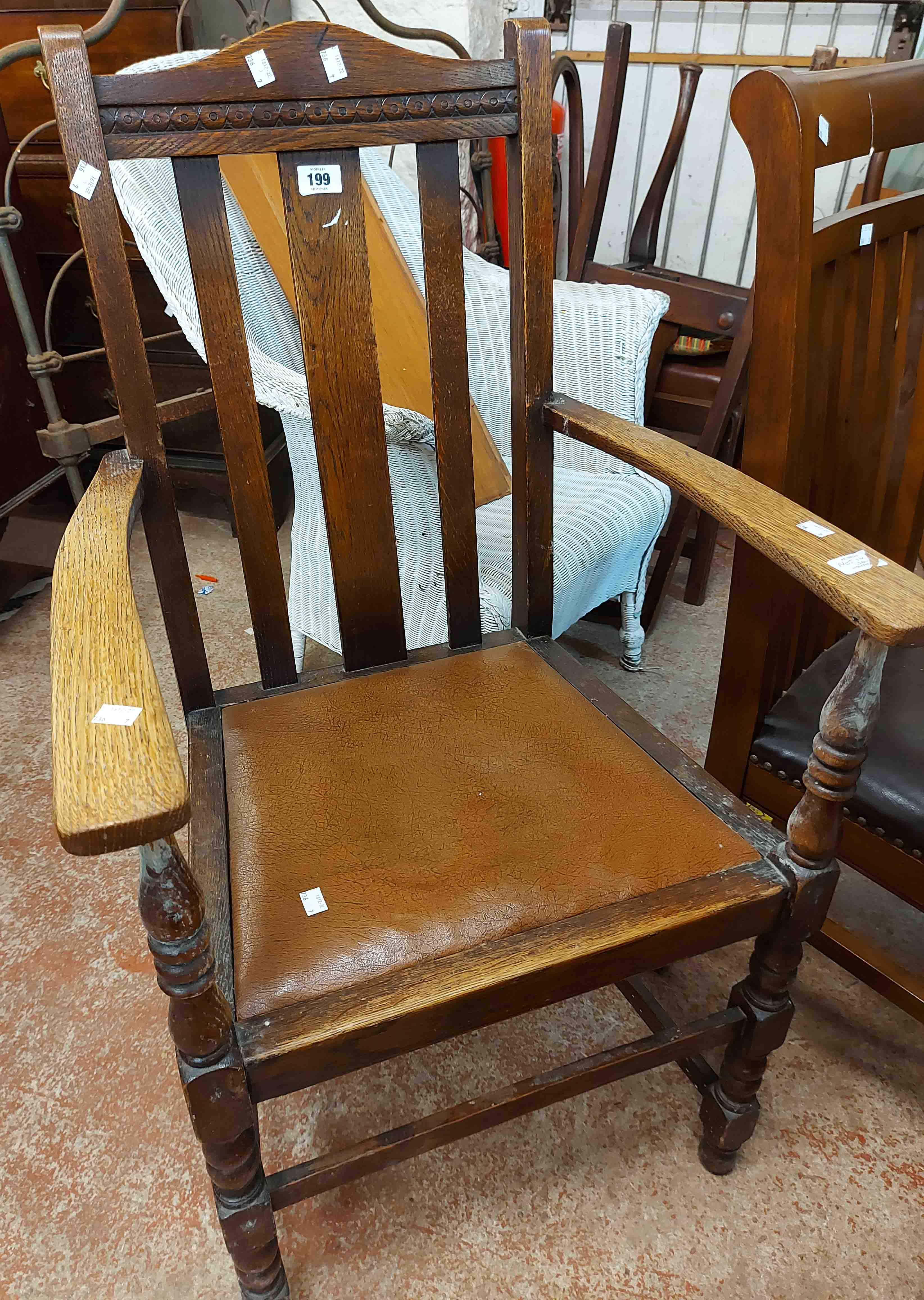 An early 20th Century oak framed lathe back carver chair with rexine drop-in seat