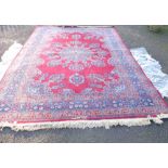 A hand made wool Persian pattern carpet with large central medallion within a triple border on red