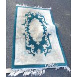 A Chinese washed wool rug with floral motifs on green ground - 1.5m X 90cm - grubby