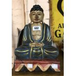 A modern carved wood and painted figurine depicting a Buddha