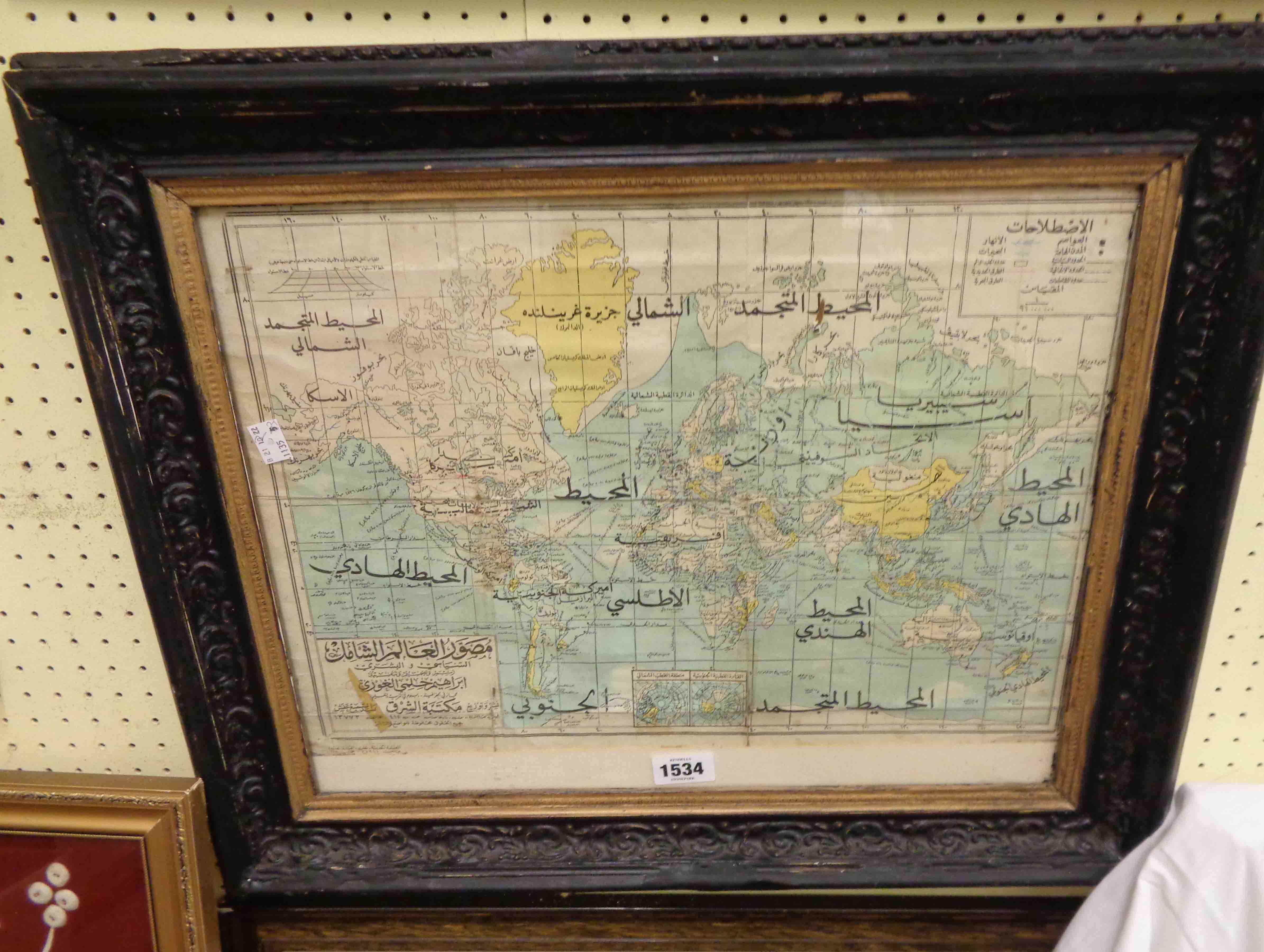 A framed old coloured map print of the world with Arabic text