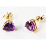 A pair of marked 375 yellow metal stud earrings, each set with a rounded triangular amethyst -