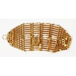 A 375 (9ct.) gold wide gate-link bracelet with tapered ends, heart shaped padlock and safety chain -