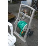 A garden hose reel, set on a wheeled base